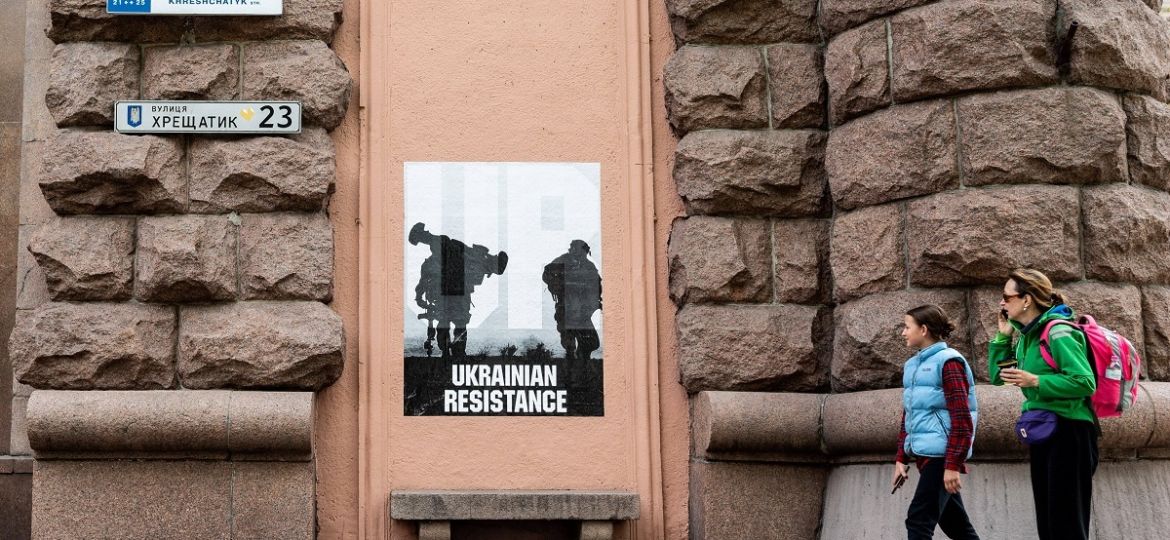 May 13, 2022, Kyiv, Ukraine: Two people seen looking at a poster on the wall of a building showing two soldiers with one